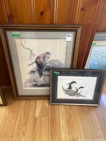 Both framed prints upright against wall showing relative sizes and framing