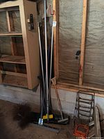 Long-handled tools leaning against wall