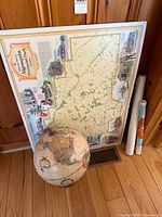 Globe, framed Algonquin pictorial map, two rolled maps leaning against wall