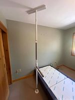 Full view of tension pole installed between floor and ceiling beside bed