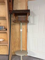 Full view of feeder on stand with birdhouse leaning beside