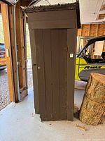 Front view of tall dark brown plank cabinet with metal roof
