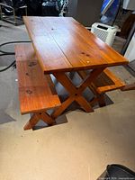 Angled view of table and benches displaying X-style legs and wood finish