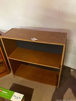 Front view of rectangular two-shelf laminate bookcase showing shelves and darker back panel