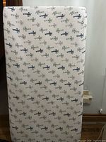 Front view of crib mattress displaying airplane pattern and overall condition