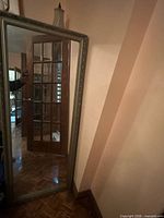 Full view of mirror leaning against wall showing size and frame design
