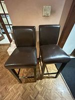 Front view of two matching dark brown faux leather bar stools