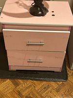 front view of nightstand showing two pink drawers and brushed nickel handles
