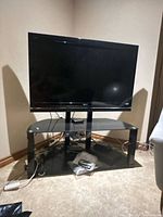 Full view of Sony TV on glass stand with cables