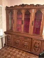 front view showing glass doors, lower storage, carved details
