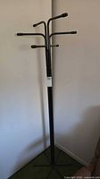 Full view of black metal freestanding coat rack in corner