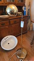 Full view of brass tone floor lamp showing spherical shade and stand