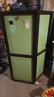 Front and left side of green cabinet with black frame