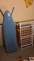 Full-size ironing board beside folded white rack