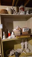 Overview of shelves showing assorted unpainted bisque pieces, painted snowman, planter and figurines