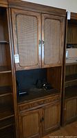 Front view of entire cabinet showing upper cane doors, middle shelf, lower cane doors