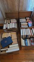 Four boxes filled with mixed paperback and hardcover fiction books