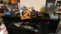 Overall view of shelf with soldering tool, bit sets, pulley blocks and assorted tools