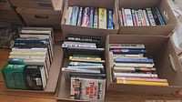 Three cardboard boxes filled with assorted fiction, military and cookbooks