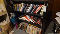 Three-shelf metal bookcase filled with mixed books