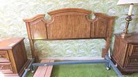 Front view of queen oak-finish veneered wood headboard attached to metal bed rails