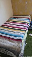 Twin mattress and box spring covered by striped quilt