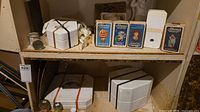 Shelf showing boxed molds, strapped plaster molds, cans and straps