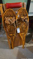 Full view of both wooden snowshoes leaning against a chair