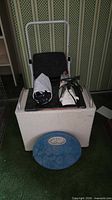 Group view showing wicker hamper, folded step stool on top with iron and bag
