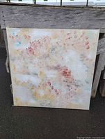 Full view of square abstract painting leaning against wood surface