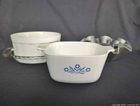 Front view showing CorningWare square casserole, Pfaltzgraff round casserole nested in glass dish, and stack of metal fluted molds