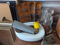 Group shot of all items including muffin pans, rolling pin, chamber pot, enamel creamer, milk bottle, sad iron, crank tool