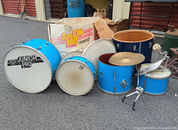 All drum shells, cymbal on stand, pedal, box in background