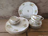 Stack of dinner and dessert plates with teacup and saucer on top, showing floral pattern and gilt edges
