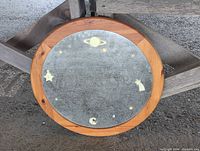 Front view of round mirror with wooden frame and celestial designs