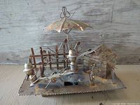Full view of copper/brass music box scene with figures, umbrella, fence and shed