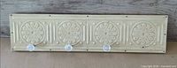 Full view of cream pressed metal rack with three glass knobs