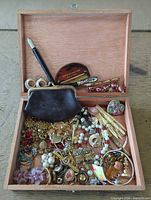 Overall view of open wooden box showing mixed costume jewelry and accessories