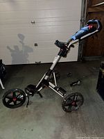 Full view of unfolded Clicgear three-wheel push cart showing frame, wheels and handle