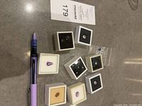 Overview of eight gem cases and pen for scale