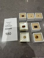 Group shot showing seven loose gemstones each in individual display boxes