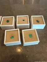 Group shot of five emeralds in boxes