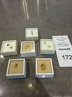 Six gem display boxes holding 9 loose gemstones; shows overall lot