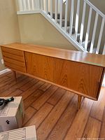 Full view of teak sideboard credenza showing drawers, sliding door and tapered legs