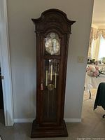 Full front view of the grandfather clock showing oak case and glass door