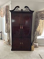 Closed mahogany armoire showing pediment and full height