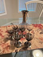 Front view of six wine glasses arranged around decanter on table