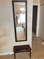 Wall-mounted rectangular mirror above matching bench