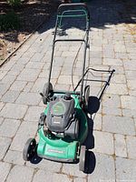 Full view of green Certified push lawn mower on stone driveway
