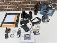 Overall view of all cameras, printer, lenses, easel and accessories on table